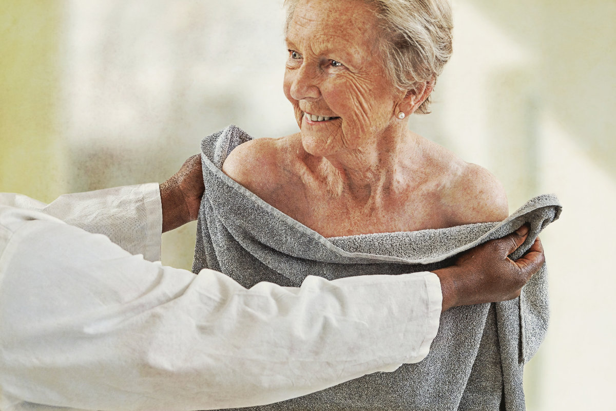 a personal support worker helping an elderly lady dry after a shower